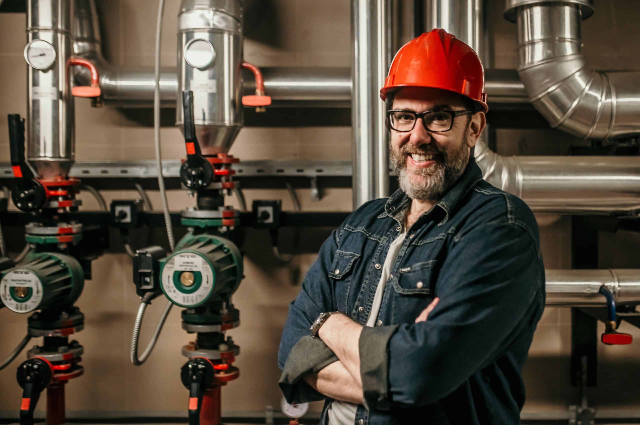 Professional plumbing standing in front of piping system