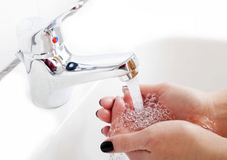 Person washing hands under a new sink with warm water