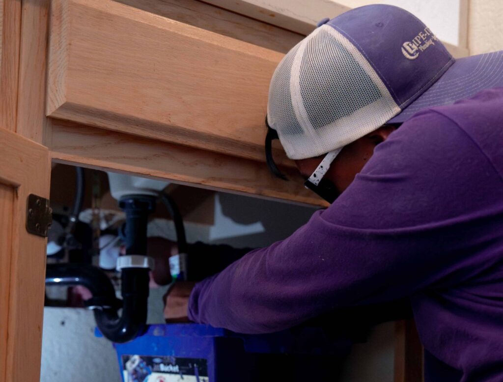 Plumber repairing the drain under a bathroom sink