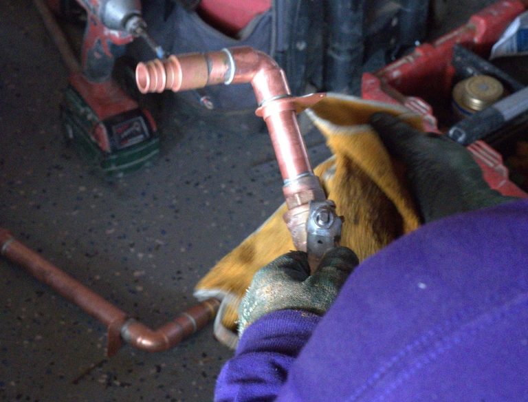 Plumbing technician cleaning a copper pipe portion to install in a house