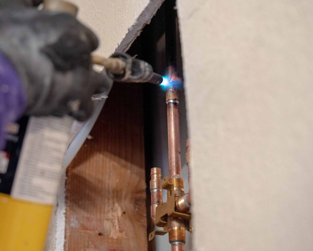 Plumber welding a copper pipe for a repiping job