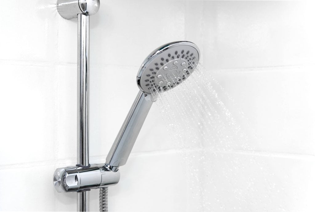 Closeup photo of a showerhead in a bathroom with white tile