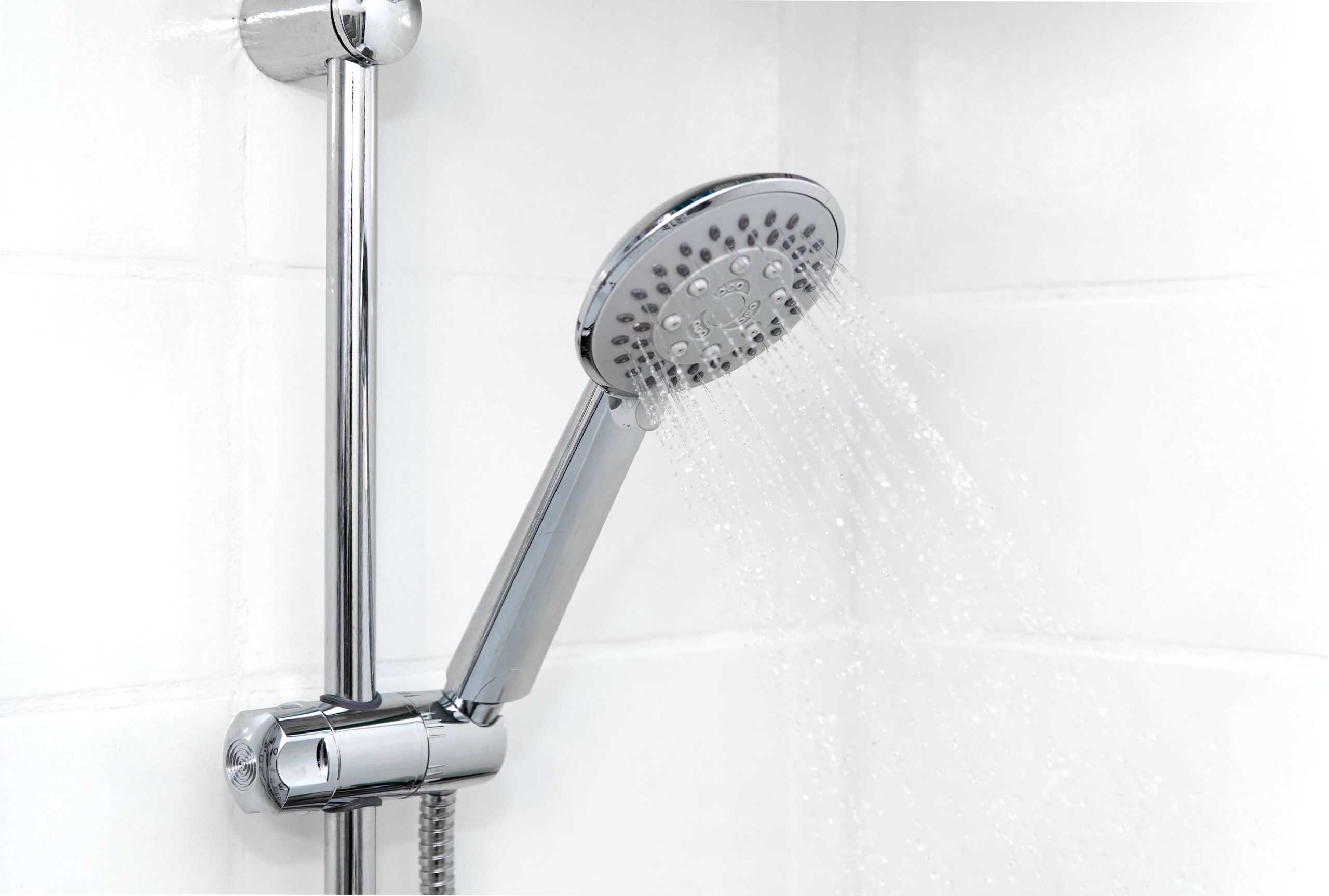 Closeup photo of a showerhead in a bathroom with white tile